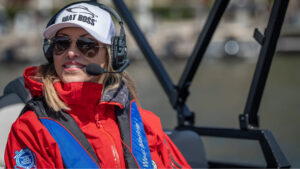 Boat Boss instructor wearing a headset and red life jacket on a boat