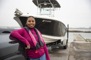 Woman in a pink life jacket beside a boat at the ramp